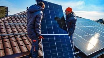 deux techniciens installent un panneau solaire sur un toit