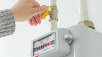 une main ferme un compteur de gaz