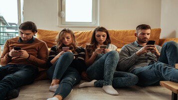 4 amis sur un canapé consultant chacun son mobile