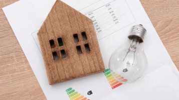 Maquette de maison en bois et ampoule posées sur un document DPE, illustrant la réouverture de MaPrimeRénov' 2026