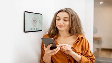 Femme contrôlant son chauffage avec un appareil connecté