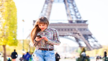 Jeune femme sur son téléphone portable devant la Tour Eiffel