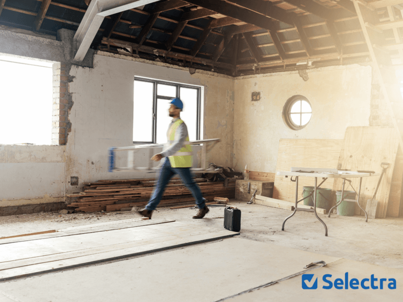 Artisan en gilet jaune marchant dans un chantier de rénovation intérieure