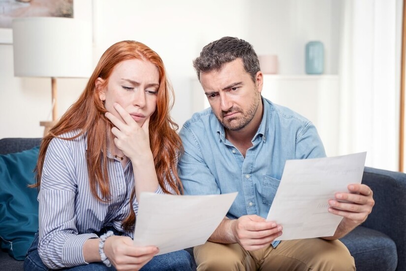 couple inquiet lit du courrier sur son canapé