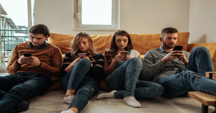 4 amis sur un canapé consultant chacun son mobile