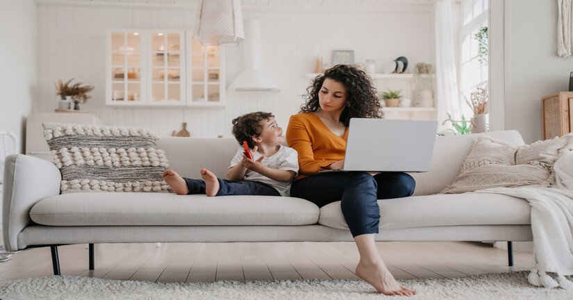 Femme sur son ordinateur portable avec son enfant jouant avec un smartphone près d'elle