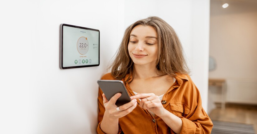 Femme contrôlant son chauffage avec un appareil connecté