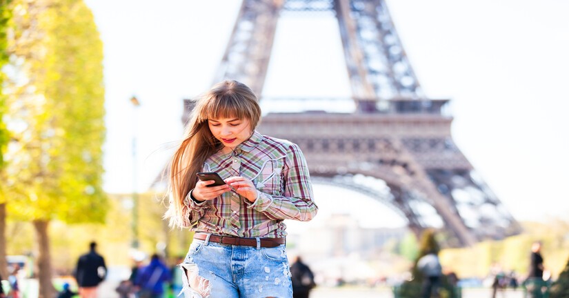 Jeune femme sur son téléphone portable devant la Tour Eiffel